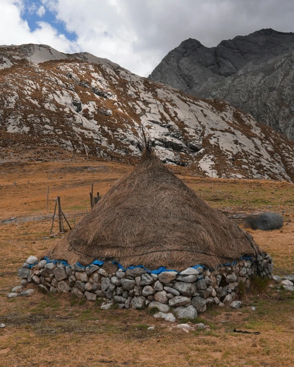 a hut sitting on top of a dry grass covered field, standing in front of a mountain, celtic culture, slide show, multiple stories