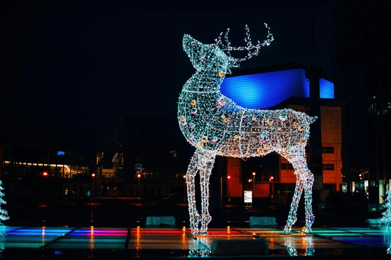 the lighted deer sits in a park in the middle of a city at night