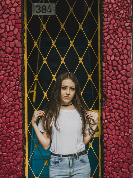 a girl poses by a gate holding her wrist