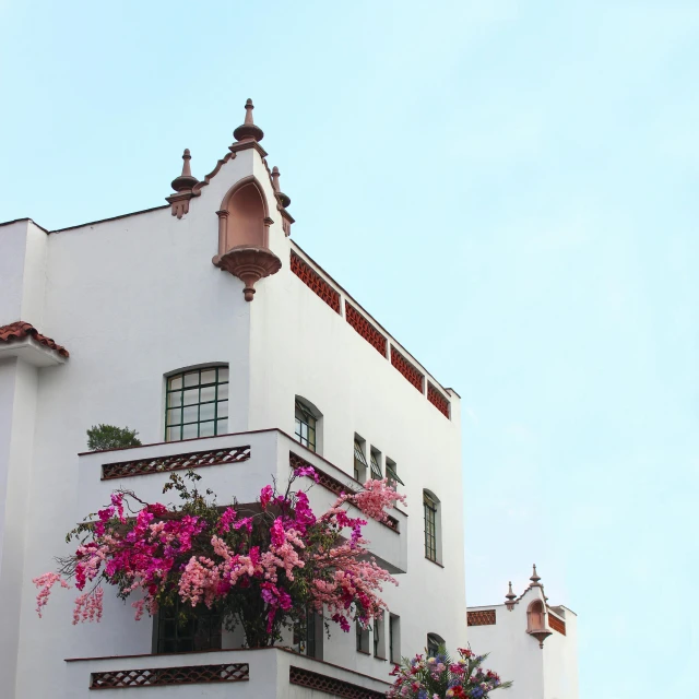 a tall building with a bunch of flowers on it, inspired by Ricardo Bofill, unsplash, art nouveau, marbella, rooftop romantic, colonial, maroon and white