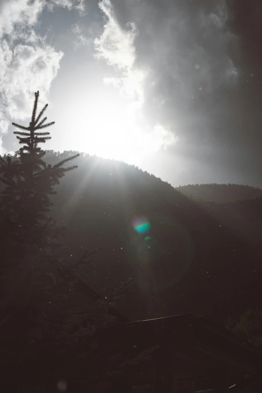 a black and white photo of the sun in the sky, inspired by LeConte Stewart, unsplash, light and space, ominous! landscape of north bend, lens flare photo real, color graded, hiking in rocky mountain