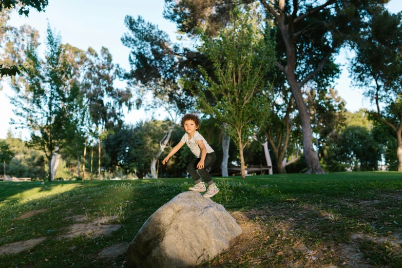a young boy riding a skateboard on top of a rock, by Michael Goldberg, unsplash, happening, botanic garden, lunging at camera :4, at the park, julia fuentes