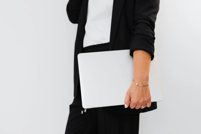 a woman talking on a cell phone while holding a laptop, by Carey Morris, minimalism, subject detail: wearing a suit, white and black clothing, a round minimalist behind, white sleeves