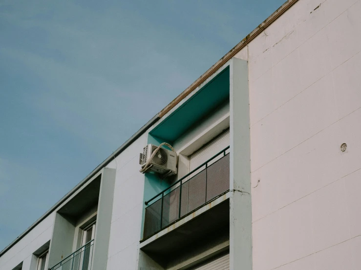 an air conditioner on the side of a building, inspired by Elsa Bleda, pexels contest winner, brutalism, teal, low quality photo, old apartment, white minimalist architecture