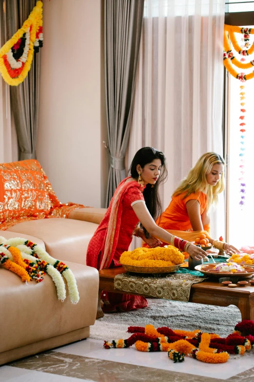 two women dressed in red and yellow standing in front of a couch