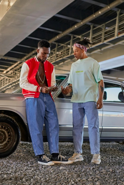 a couple of men standing next to a silver car, an album cover, by Balcomb Greene, trending on pexels, visual art, green corduroy pants, playboi carti portrait, wearing correct era clothes, calmly conversing 8k