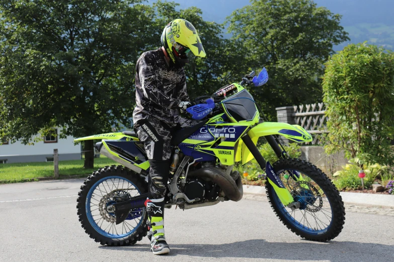 a man riding on the back of a yellow dirt bike, wearing a neon blue hoodie, lime green, avatar image, professional image