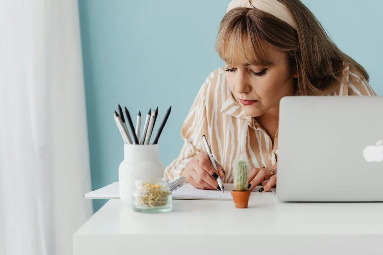a woman sitting at a desk working on a laptop, a drawing, by Julia Pishtar, pexels contest winner, pen and paper, hunched over, carefully designed, standing on a desk