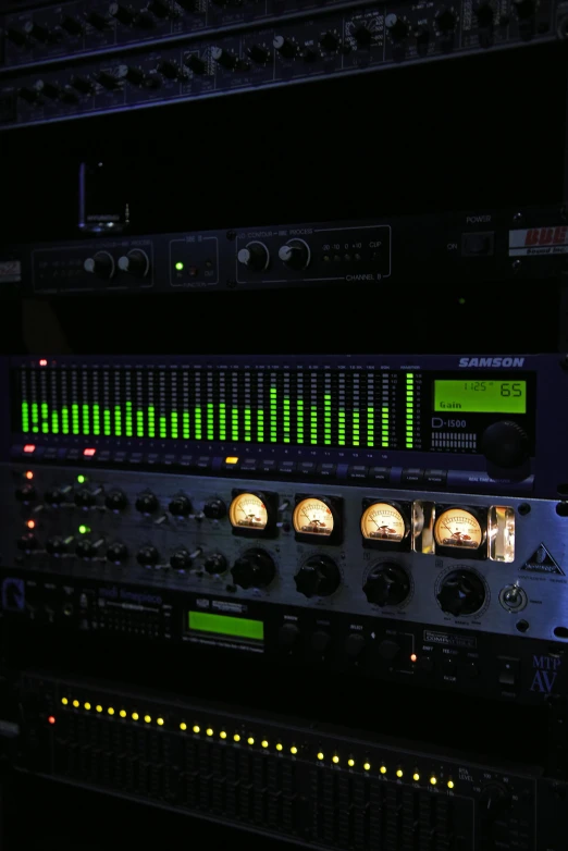 a bunch of electronic equipment sitting on top of a table, an album cover, green and purple studio lighting, tubes and gauges, rack, programming