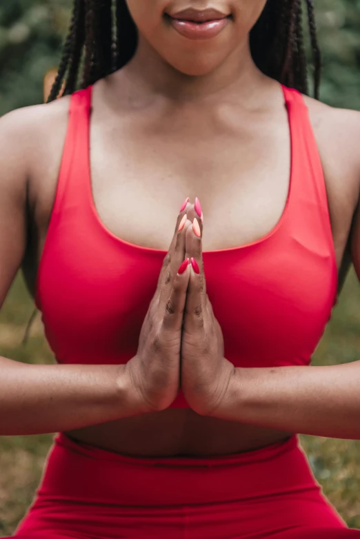 a woman in red is sitting with her hands folded in a position