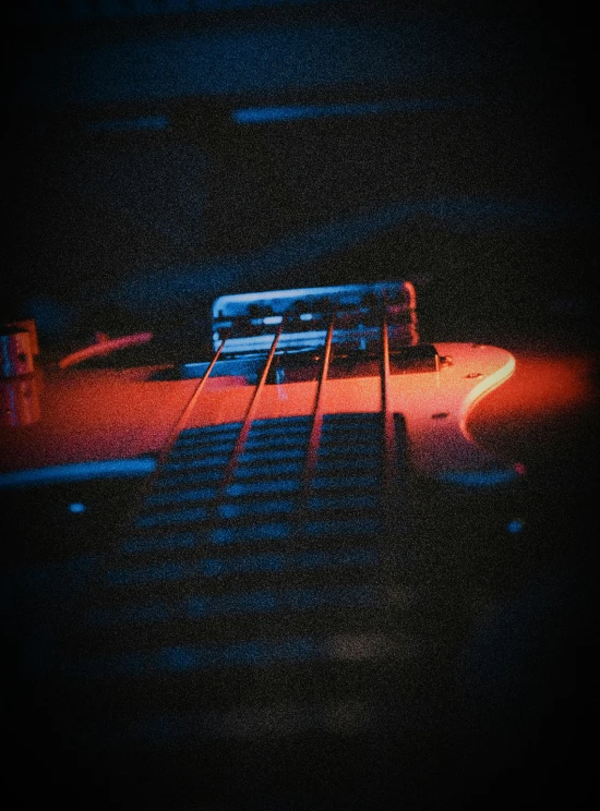 a computer keyboard sitting on top of a desk, an album cover, inspired by Elsa Bleda, unsplash, fantastic realism, playing electric guitar, muted blue and red tones, heavy grainy picture, playing guitar onstage