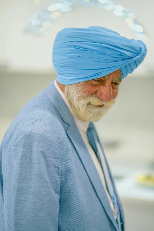 the man is wearing a blue turban and looking at his cell phone