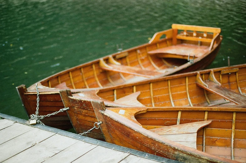 three wooden boats tied to a dock next to a body of water, by Carey Morris, pexels contest winner, arts and crafts movement, brown, romantic lead, thumbnail, zoomed in shots