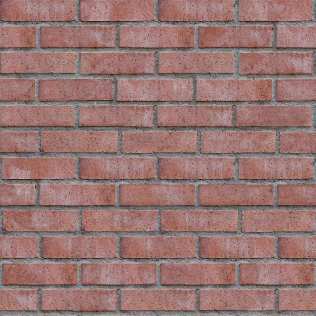 a gray cat sitting on the corner of a brick wall