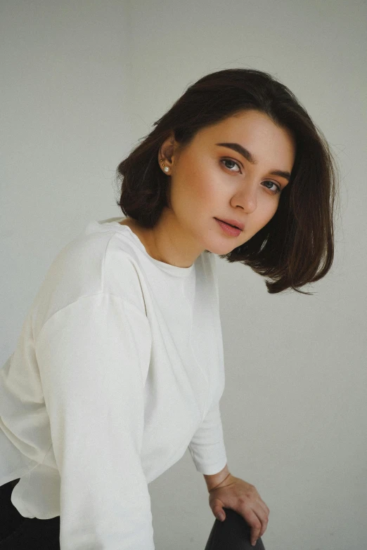 a woman sitting on top of a black chair, a character portrait, by irakli nadar, pexels contest winner, wearing a white sweater, round jawline, hana alisa omer, natural short hair