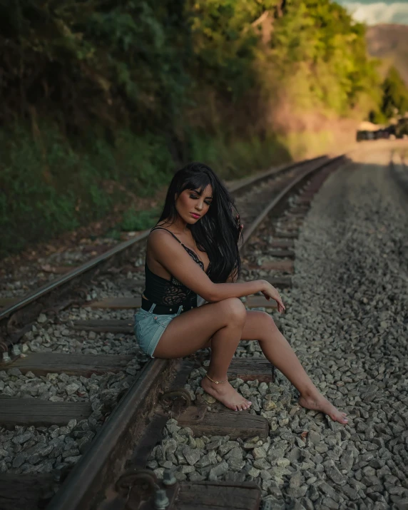 a woman is sitting on the railroad tracks