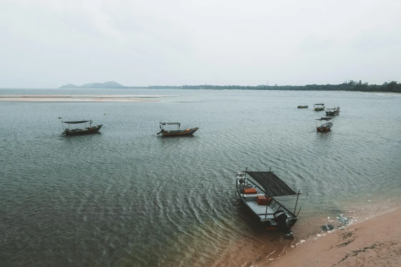 a group of boats floating on top of a body of water, by Carey Morris, pexels contest winner, grey, near the beach, myanmar, leaked image