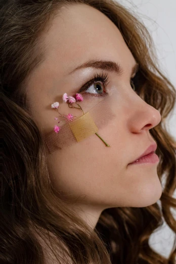 a woman with a piece of tape on her face, an album cover, inspired by Méret Oppenheim, trending on pexels, aestheticism, patchy flowers, thoughtful ), acupuncture treatment, square facial structure