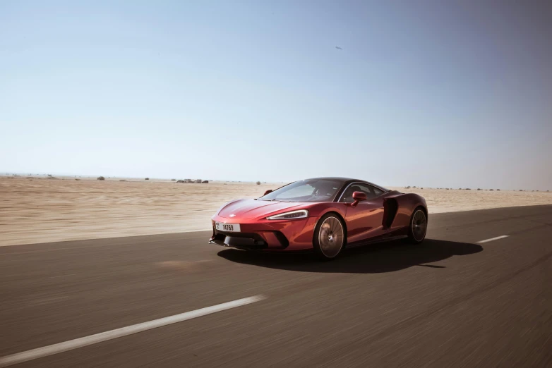 a red sports car driving down a desert road, inspired by Harry Haenigsen, pexels contest winner, mclaren, highly reflective surface, 8k cinematic shot, gulf