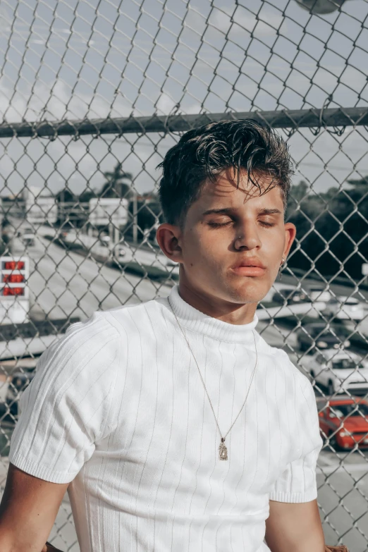 a man stands in front of a fence wearing an un - tucked white shirt