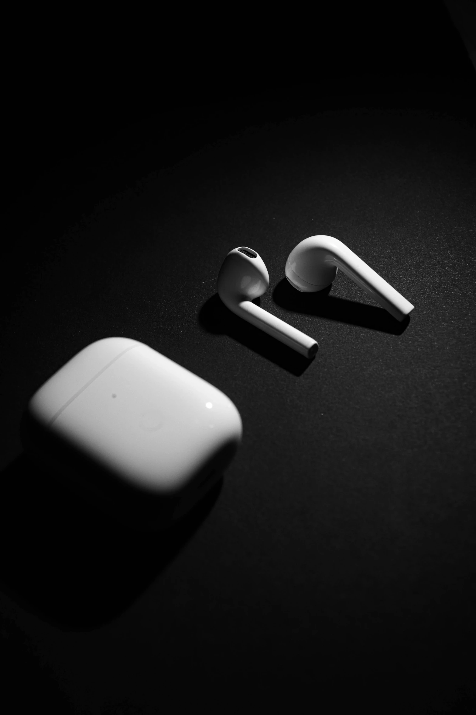 an apple airpods sitting on top of a table, a black and white photo, inspired by Robert Mapplethorpe, unsplash, out in the dark, toys, sport, an earring