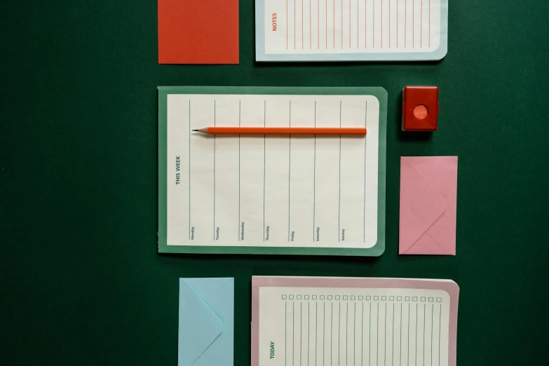 a green table topped with notepads and a pencil, inspired by Wes Anderson, trending on pexels, square lines, red and green hour, frank moth, lined up horizontally