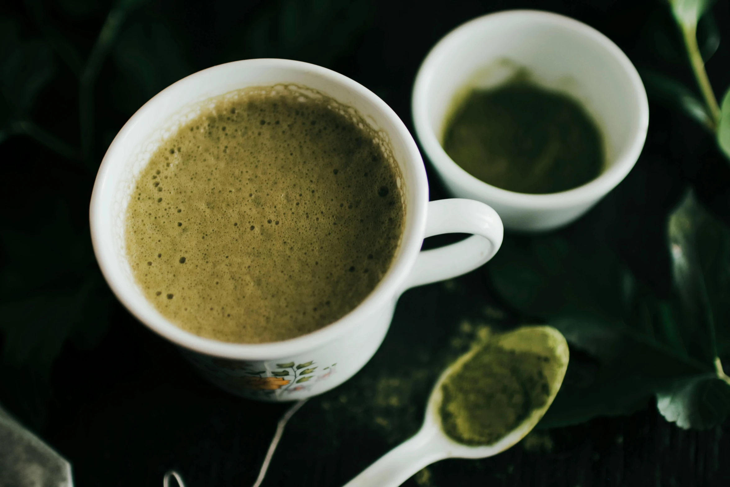 a couple of cups of green tea with spoons