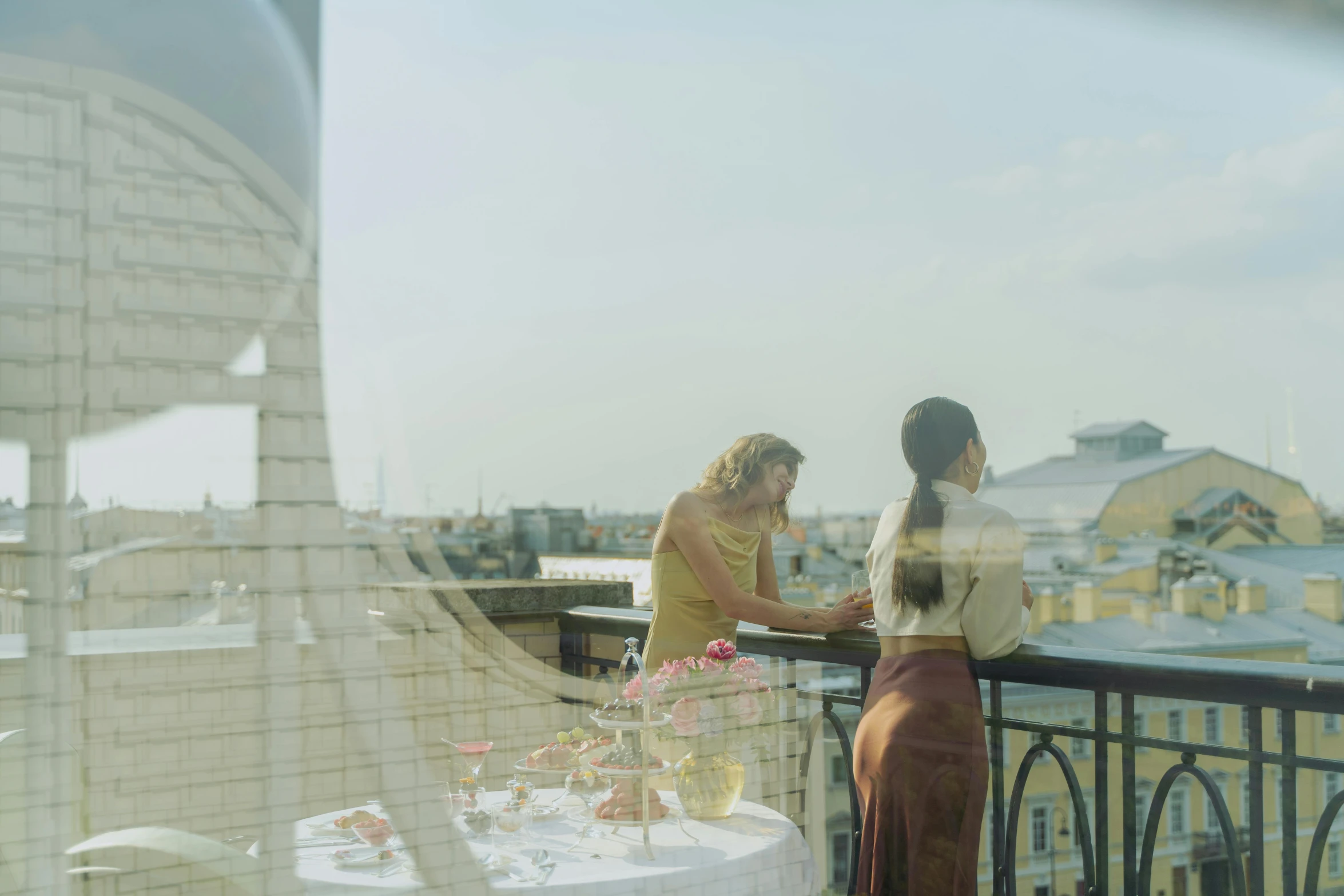 two women shake hands across a table that overlooks a city