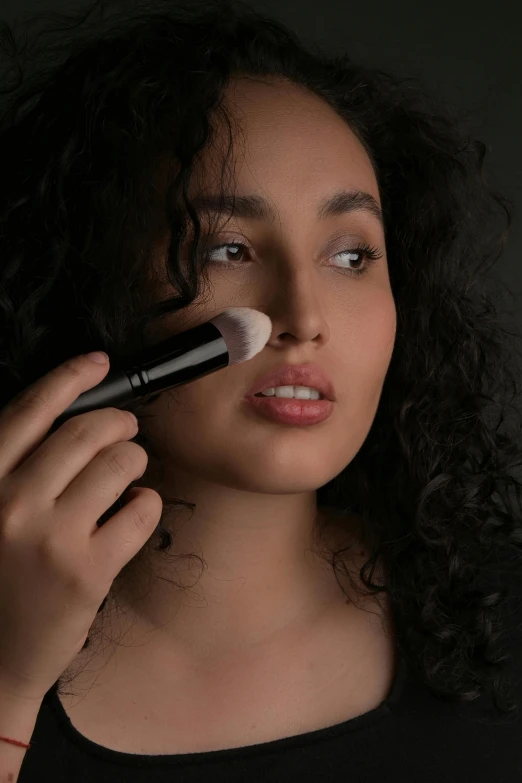 a woman brushes her makeup with a brush