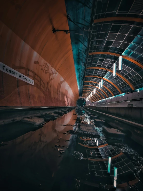 a train traveling down a train track next to a tunnel, inspired by Filip Hodas, unsplash contest winner, graffiti, water reflection on the floor, on a futuristic shopping mall, orange line, seen from below