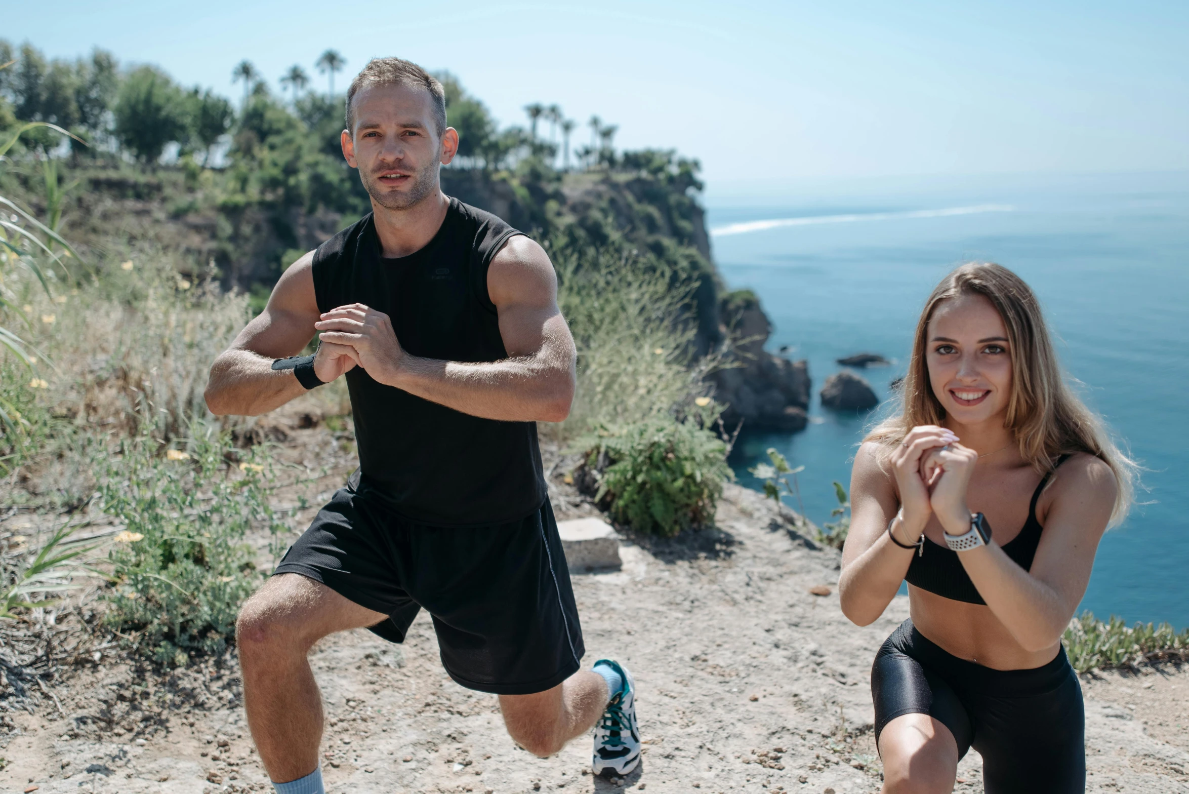 a man and woman on a trail running along the ocean