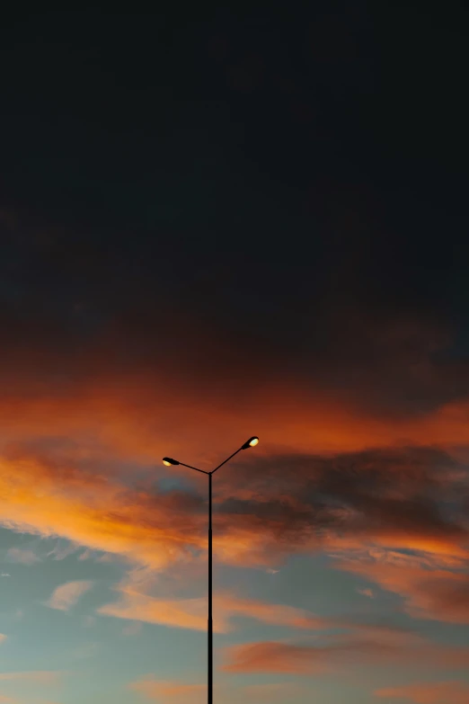 a street light sitting on the side of a road, by Alexis Grimou, red clouds, dramatic lighting - n 9, large twin sunset