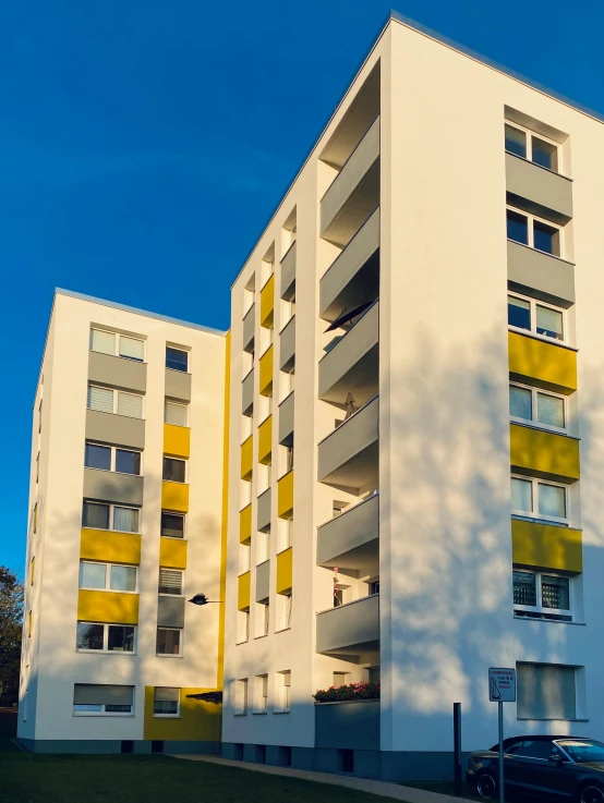 a car parked in front of a tall white building, by Kristian Zahrtmann, bauhaus, silver and yellow color scheme, 15081959 21121991 01012000 4k, detmold charles maurice, panorama