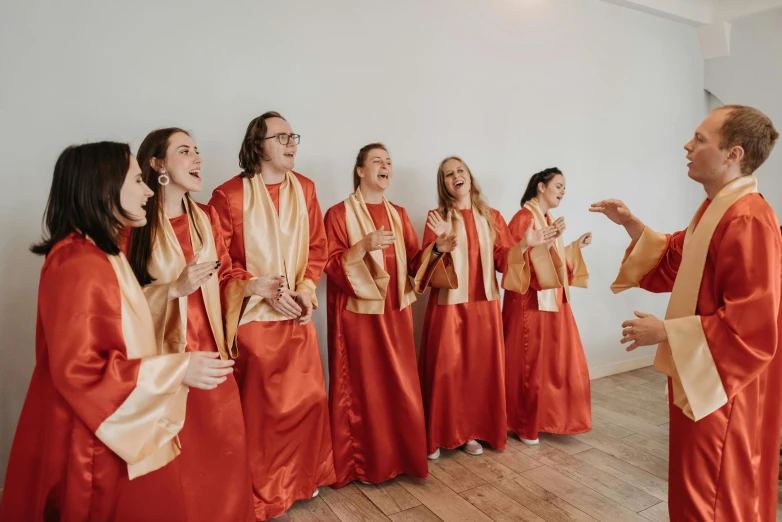a group of people that are standing in a room, an album cover, by Emma Andijewska, trending on unsplash, baroque, religious robes, joyful, 15081959 21121991 01012000 4k, wearing red and yellow clothes