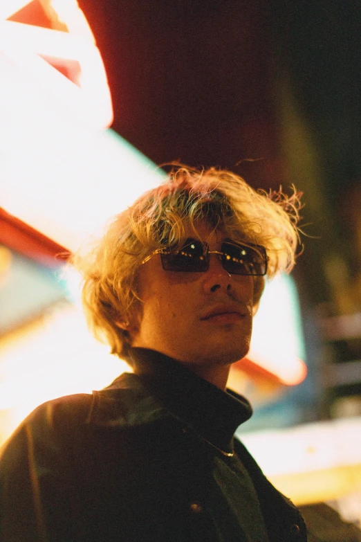 a man standing in front of a neon sign, an album cover, unsplash, rococo, blonde shaggy hair, with sunglass, ryuichi sakamoto, profile image