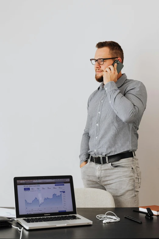 a man standing next to a desk talking on a cell phone, trending on pexels, standing posture, man with glasses, it specialist, caucasian