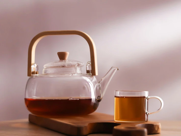 a tea pot sitting on top of a wooden table next to a cup of tea, 8 l, glassware, bamboo, frontal shot