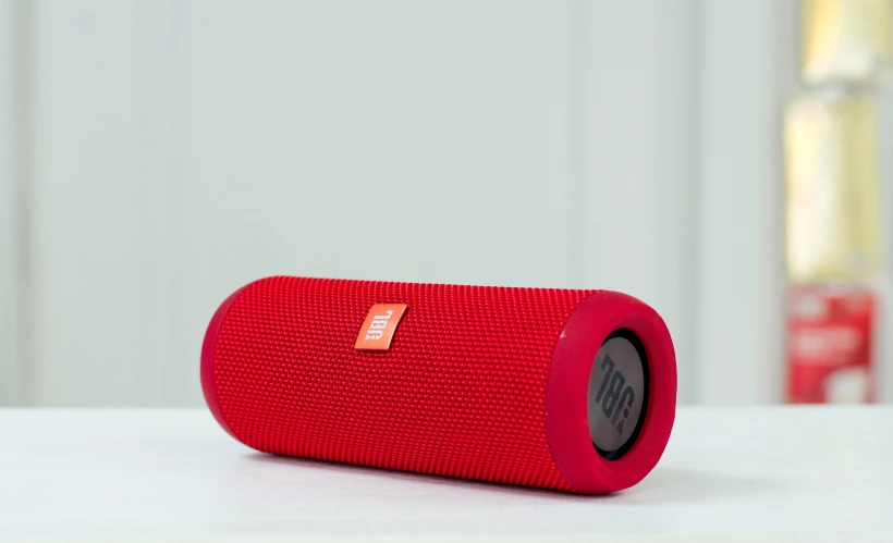 a red speaker sitting on top of a table, red fabric, matte finish, red sport clothing, battery