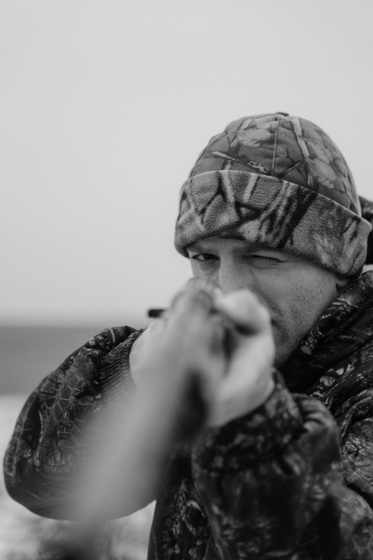 a black and white photo of a man with a gun, by Greg Rutkowski, praying with tobacco, hunter hunter, wearing camo, chilly