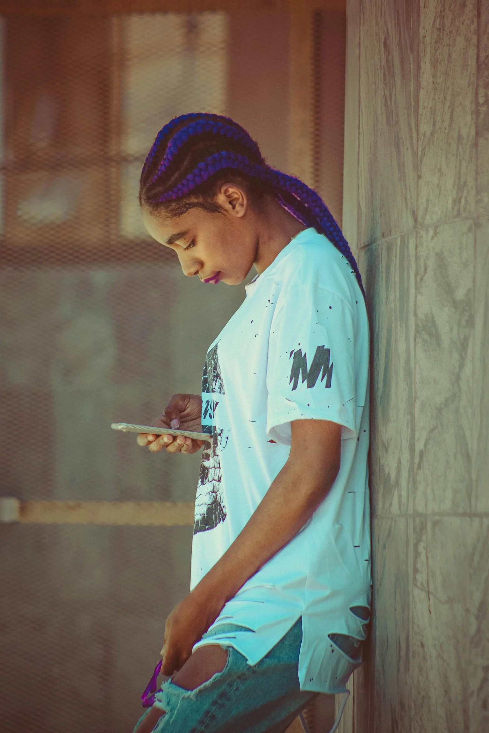 a girl leaning against a wall using a cell phone, an album cover, trending on pexels, graffiti, hair blue two long braids, black teenage boy, profile image, sad prisoner holding ipad