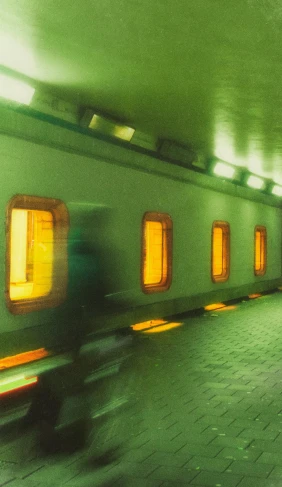 a blurry photo of a person riding a bike in a subway, an album cover, inspired by Andreas Gursky, retrofuturism, capsule hotel, 1990s photograph, yellow lights, greenish expired film