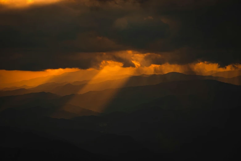 the sun is shining through clouds over the mountains