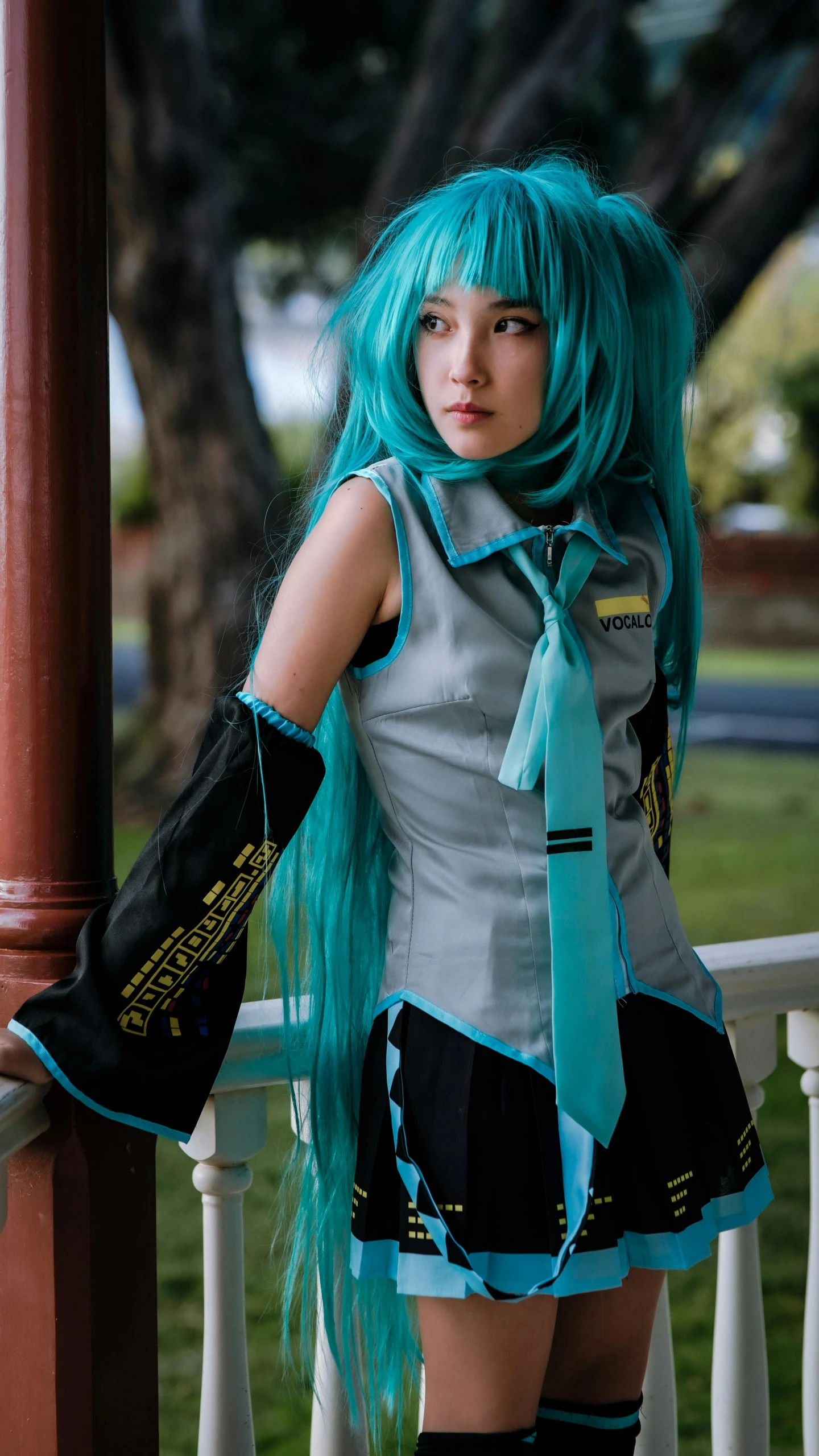 girl with green hair and tie standing near railing