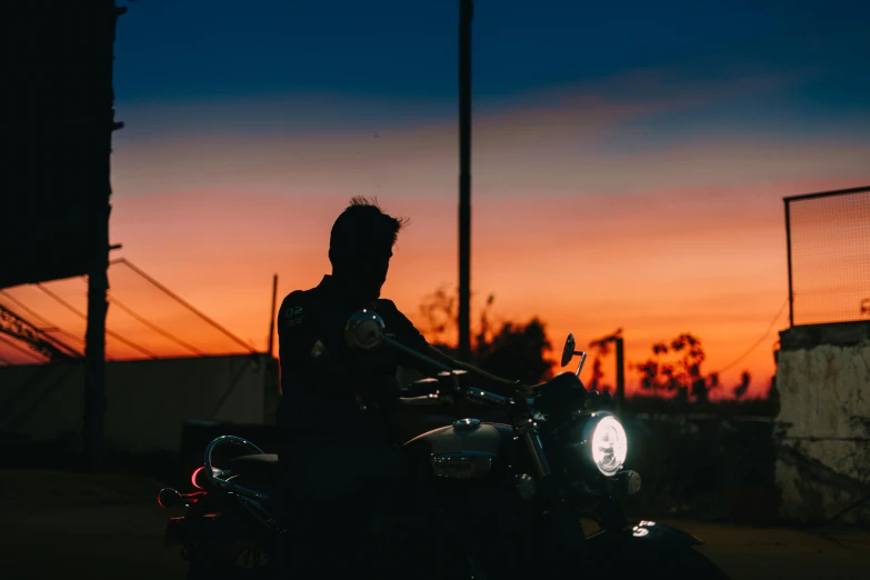 a man riding on the back of a motorcycle, by Lee Loughridge, pexels contest winner, symbolism, at twilight, profile image, looking to the side, lachlan bailey