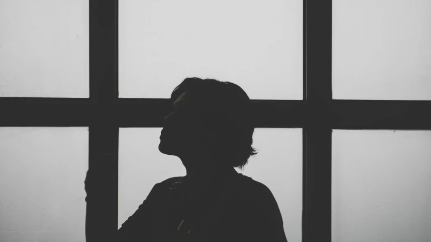 a silhouette of a woman standing in front of a window, a black and white photo, profile picture 1024px, struggling, instagram post, 40 years old women