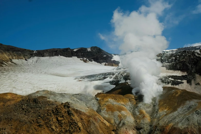 a large, yellow and white geyser spewing from the side of a snowy mountain