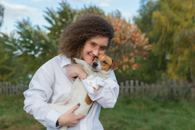 a woman holding a small dog in her arms, a photo, by Julia Pishtar, pixabay contest winner, wearing lab coat and a blouse, avatar image, autumn, 15081959 21121991 01012000 4k