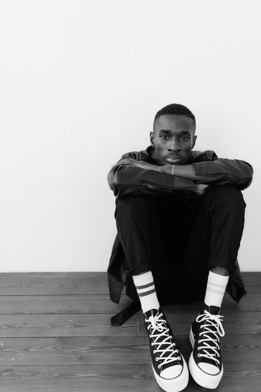 a black and white photo of a man sitting on the floor, inspired by Theo Constanté, lil uzi vert, aged 2 5, ( ( dark skin ) ), looking confident