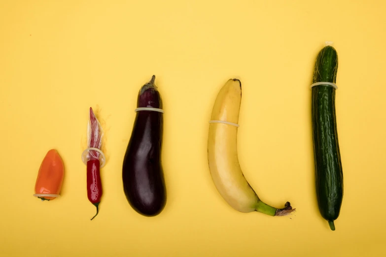 a banana, zucchini, and other vegetables laid out on a yellow surface, by Doug Ohlson, unsplash, entangled vibrating, in a row, contracept, 1 male