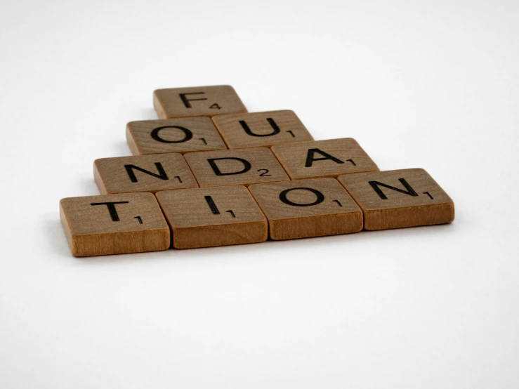 three pieces of wooden scrabble spelling out the word foundation
